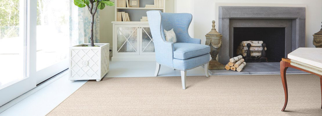Tan area rug with blue chair and white tiled living room” width=